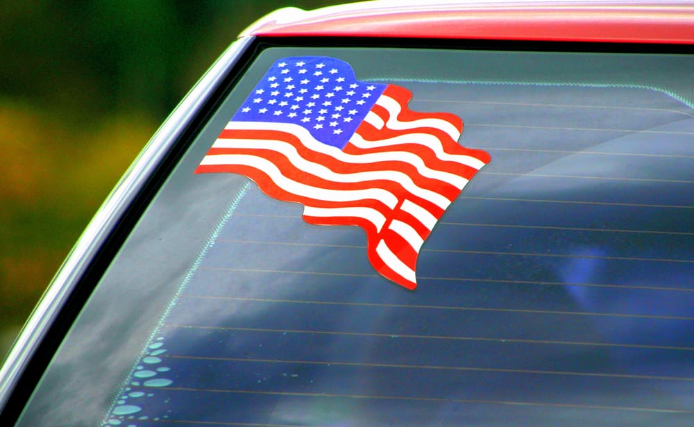 Waving American flag sticker on corner rear window of car