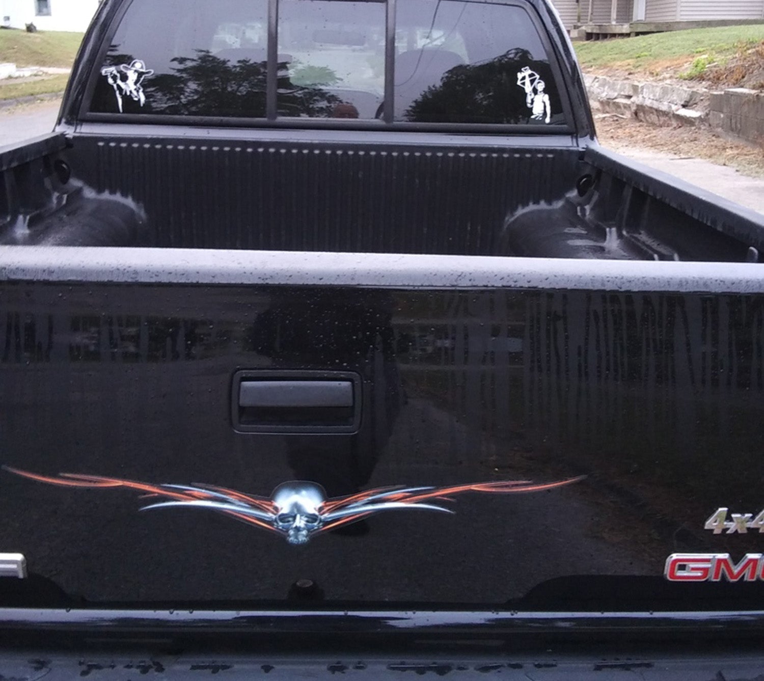 chrome horned skull tailgate decal with long pinstripe flames on a black GMC truck