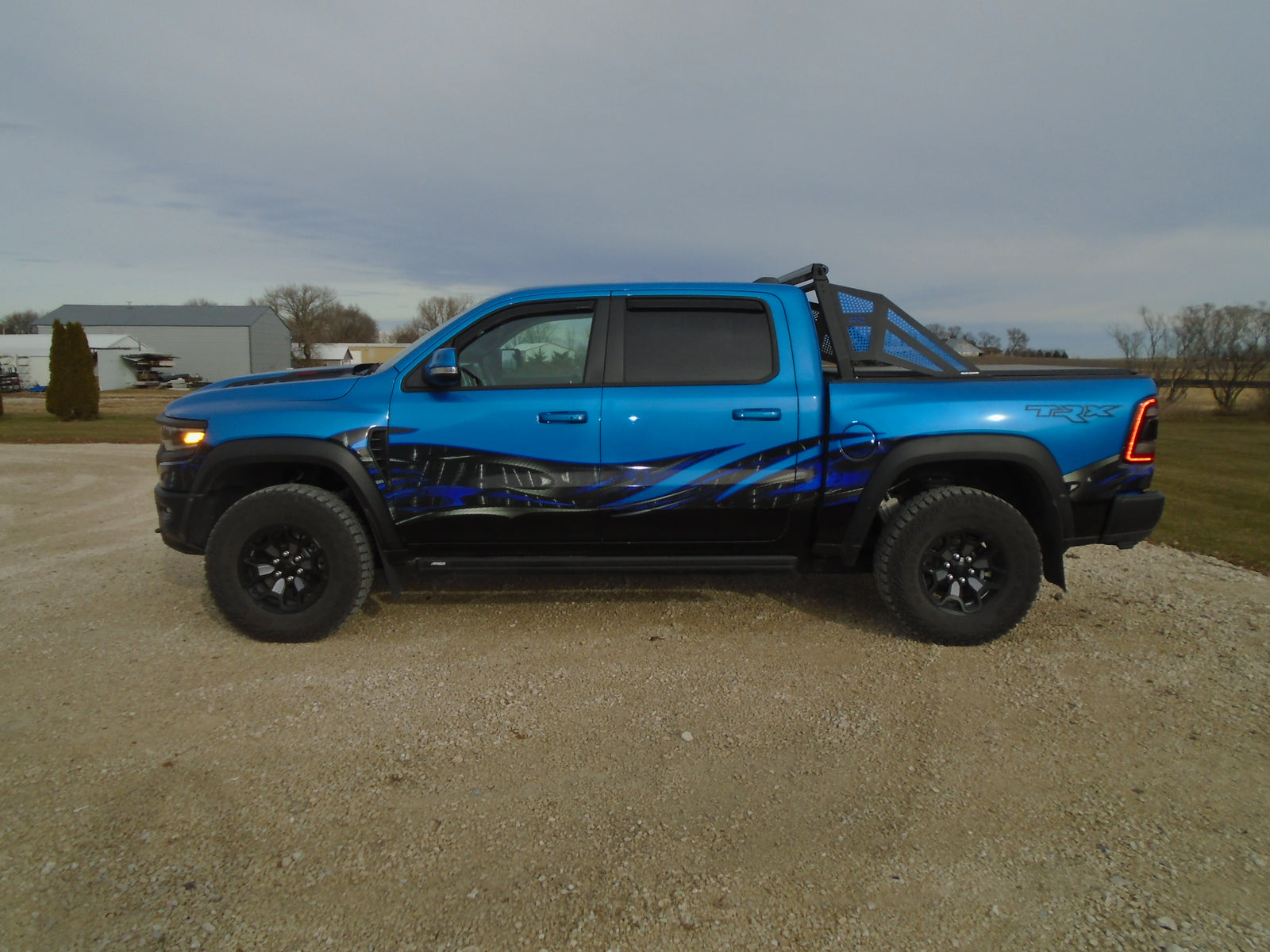 Tribal carbon fiber wave onthe side of a blue ram pickup