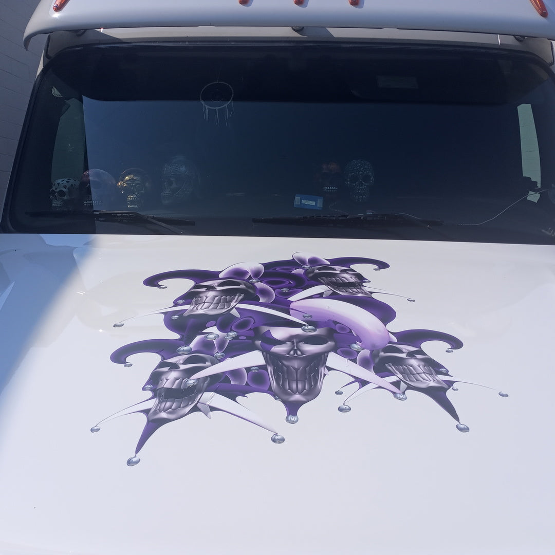 laughing skulls in purple jester hats vinyl graphics on a white truck hood