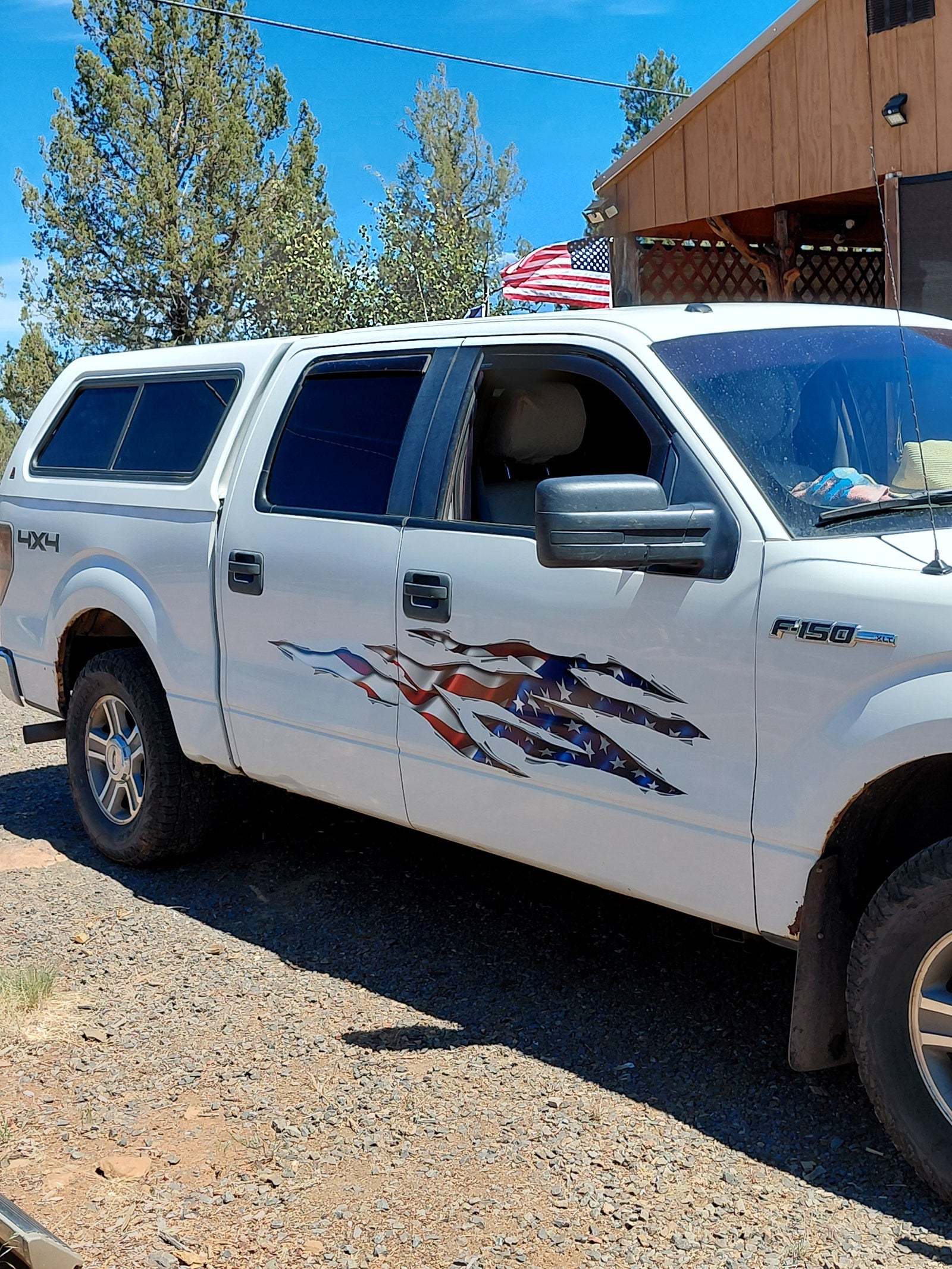Passenger side of white Ford F-150 with American Flag Big Rip vinyl decal across both doors