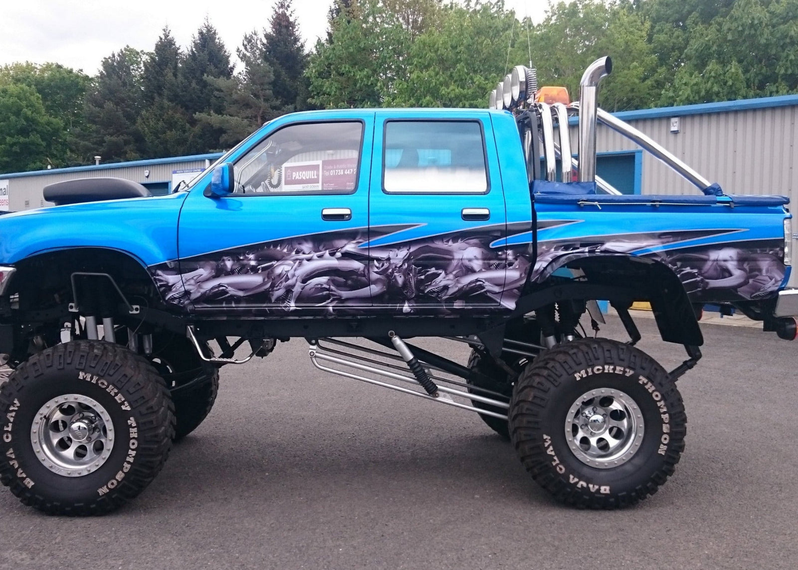 Toyota Hilux monster truck with gray dragon wrap on its side