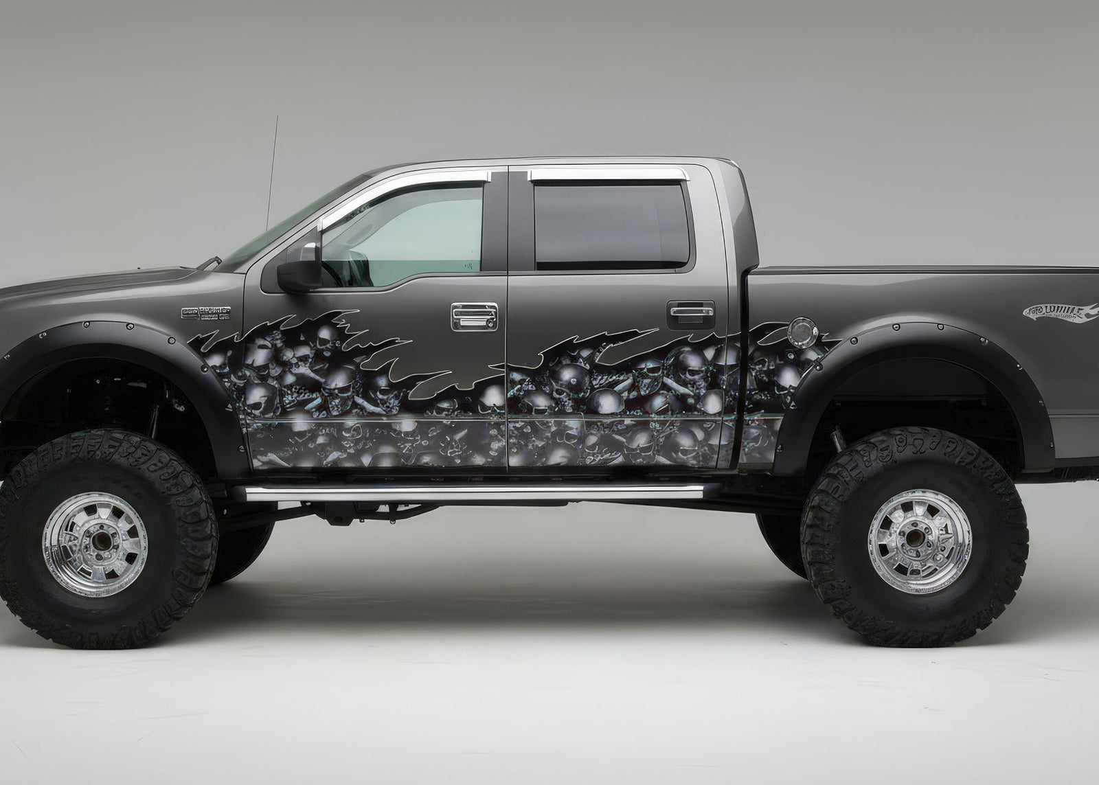Raised truck with gray skulls flames half wrap graphics on driver side