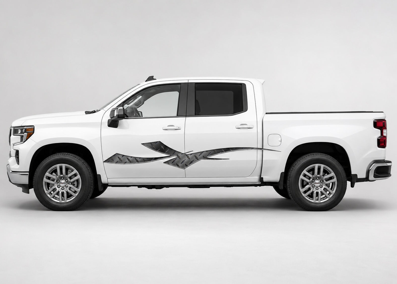 Silver and black Diamond Plate Strike vinyl graphic displayed along the driver side of a white four-door pickup truck.