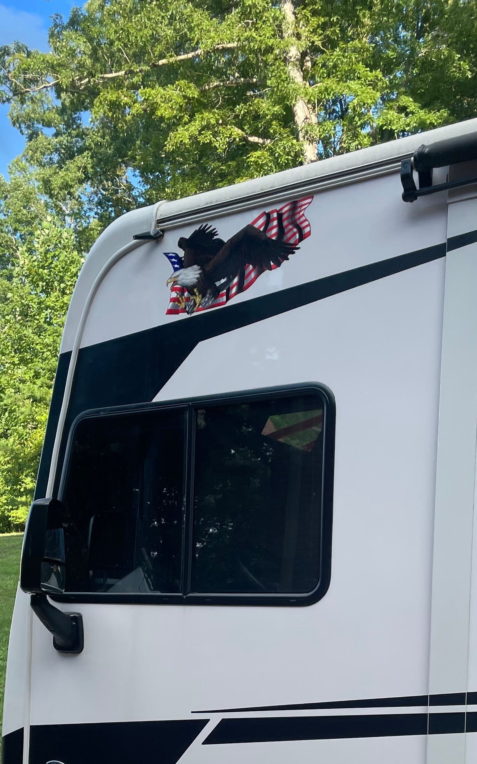 Large bald eagle American flag vinyl decal installed above the driver side window on a white RV