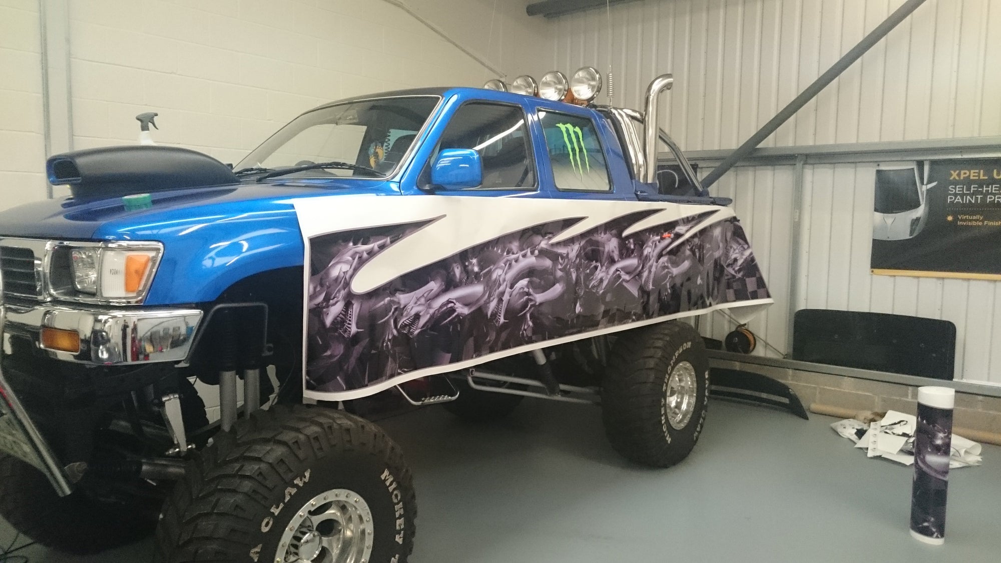 dragon half vinyl wrap being applied to blue raised toyota truck