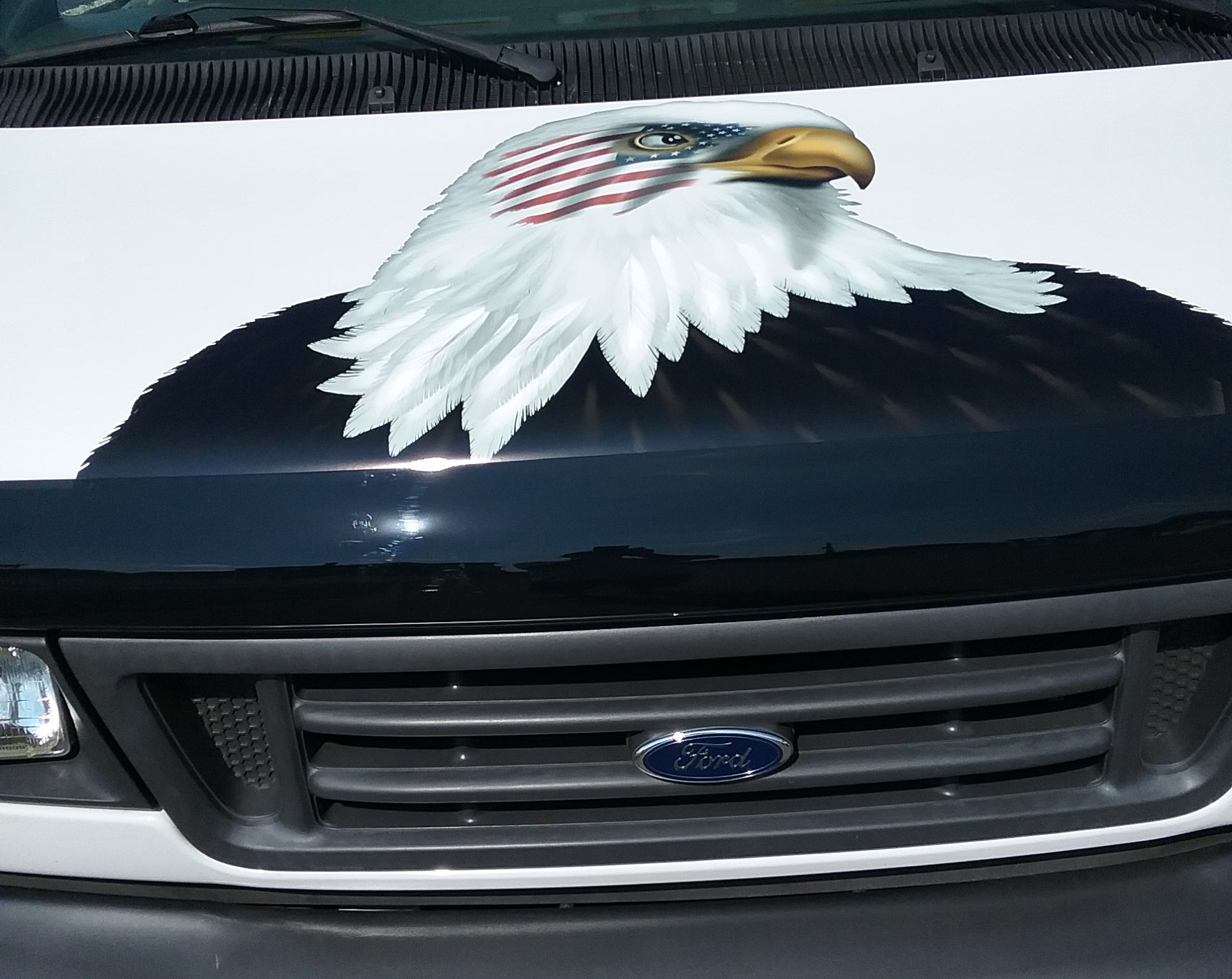 bald eagle with american flag decal on the hood of a white van