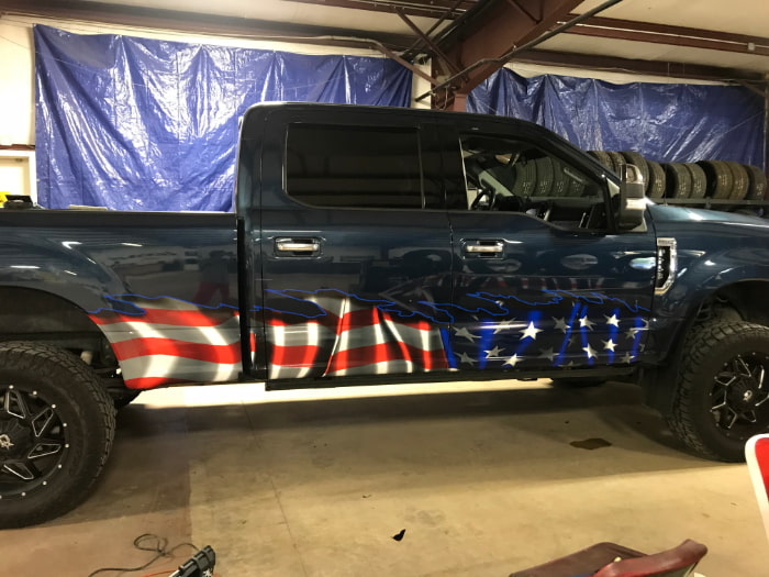 waving American flag decal on bottom half side of blue pick up truck