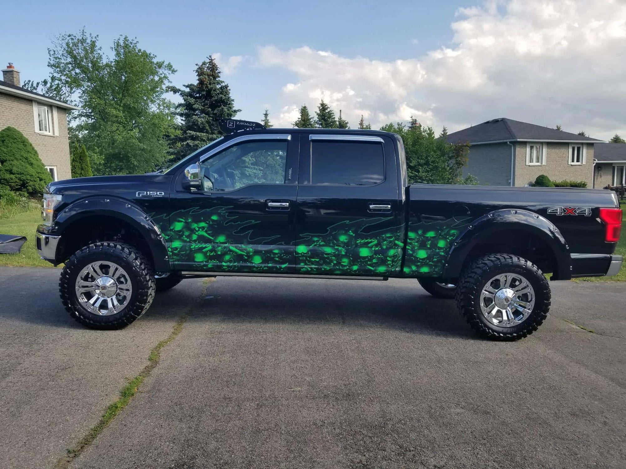 Bright green skulls wave half wrap on the side of a black pick up truck