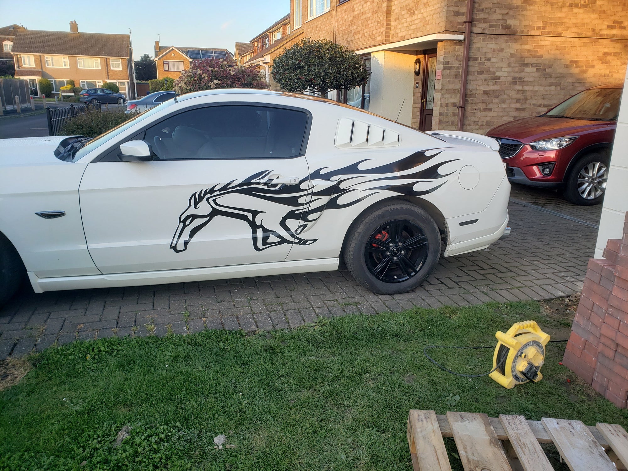 white mustang sports car with black mustang horse decal on its back side