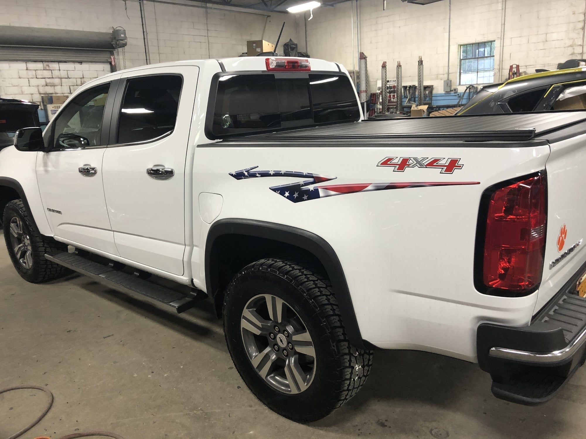 White 4x4 pickup with American flag bedside stripe decal installed