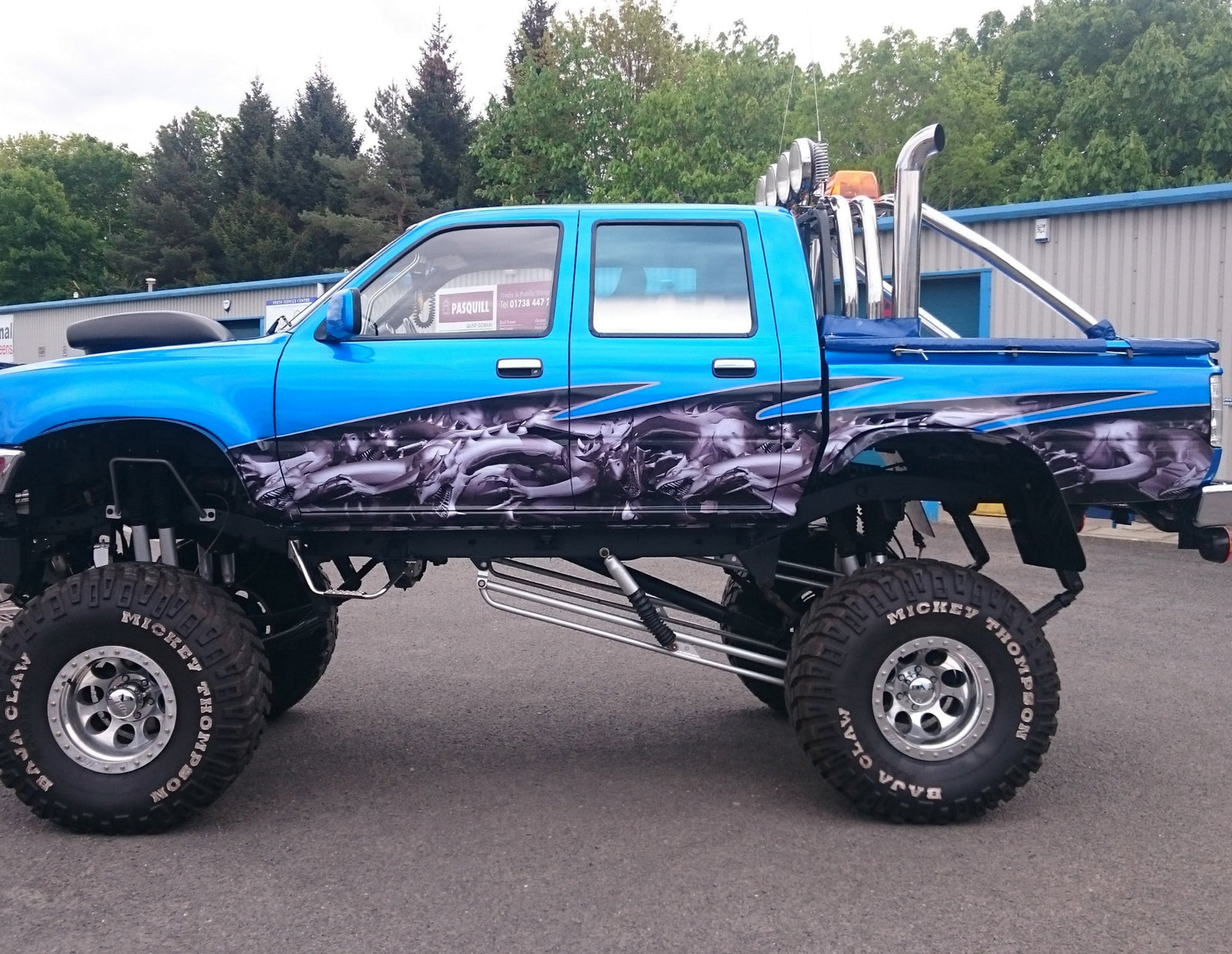 Toyota Hilux monster truck with gray dragon wrap on its side