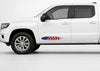 White pickup truck in driver-side profile with a small American flag feather decal on the lower front door.