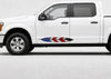 A white Ford pickup truck shown in a side profile view against a light gray studio background, featuring a red, white, and blue American flag feather decal on the lower side of the front door.