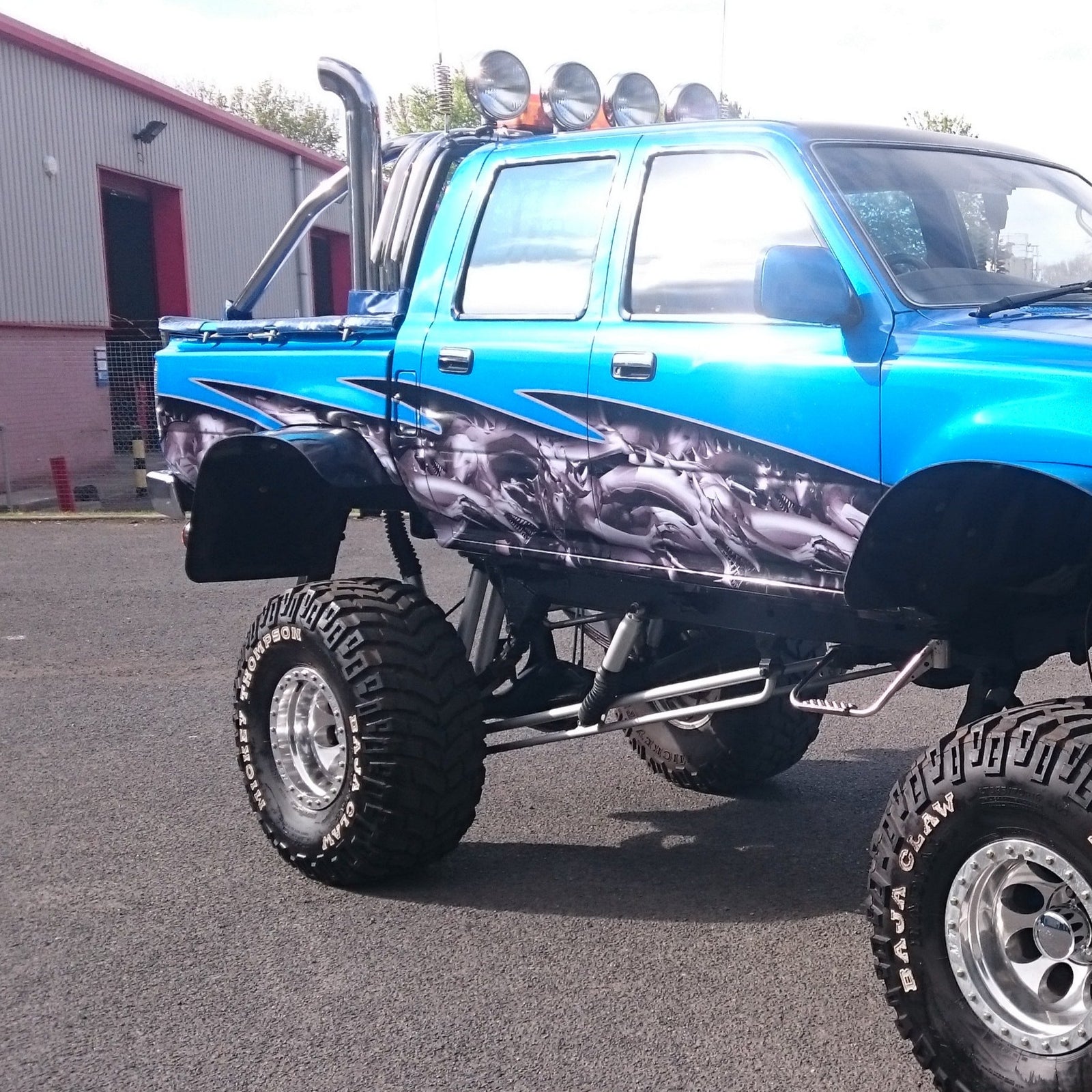Toyota Hilux monster truck with gray dragon wrap on its side