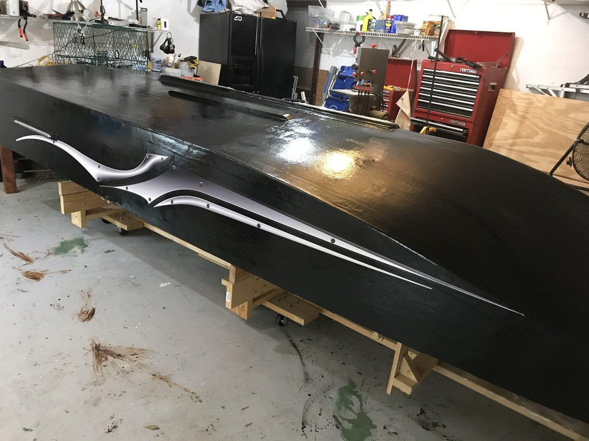 freshly painted black boat upside down being worked on in garage with sivler blade decal on its port side