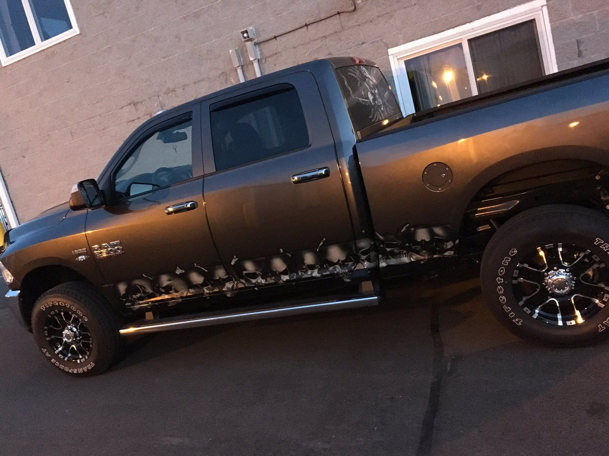 grey ram truck parked next to building with skulls & crossbones decal across its driver side rocker panel