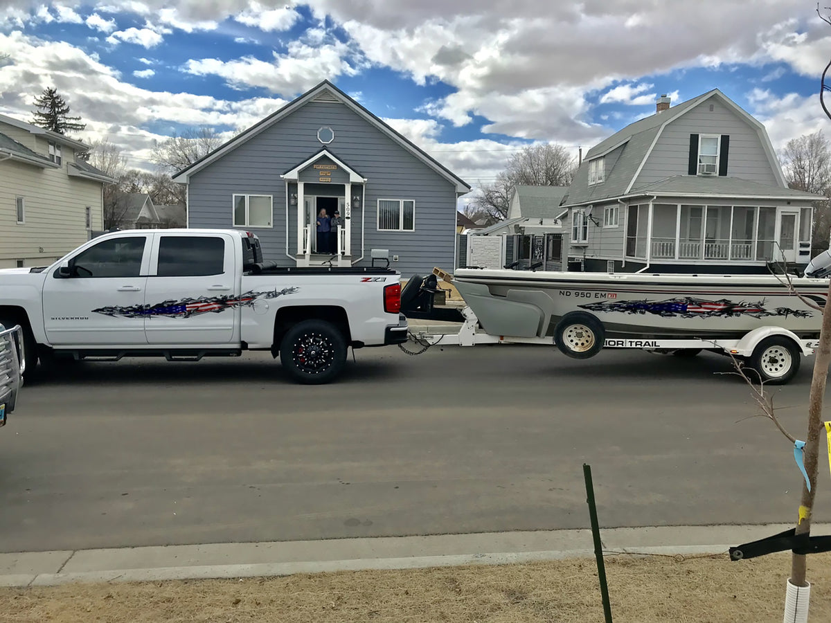 white silverado truck pulling trailer with white boat both have American flag ripper vinyl graphics on driver side