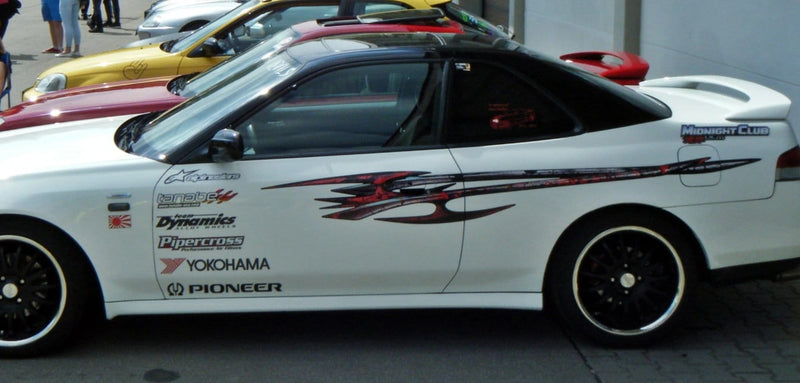 white sport car with tribal edge decal in on the driver side in car show in parking lot
